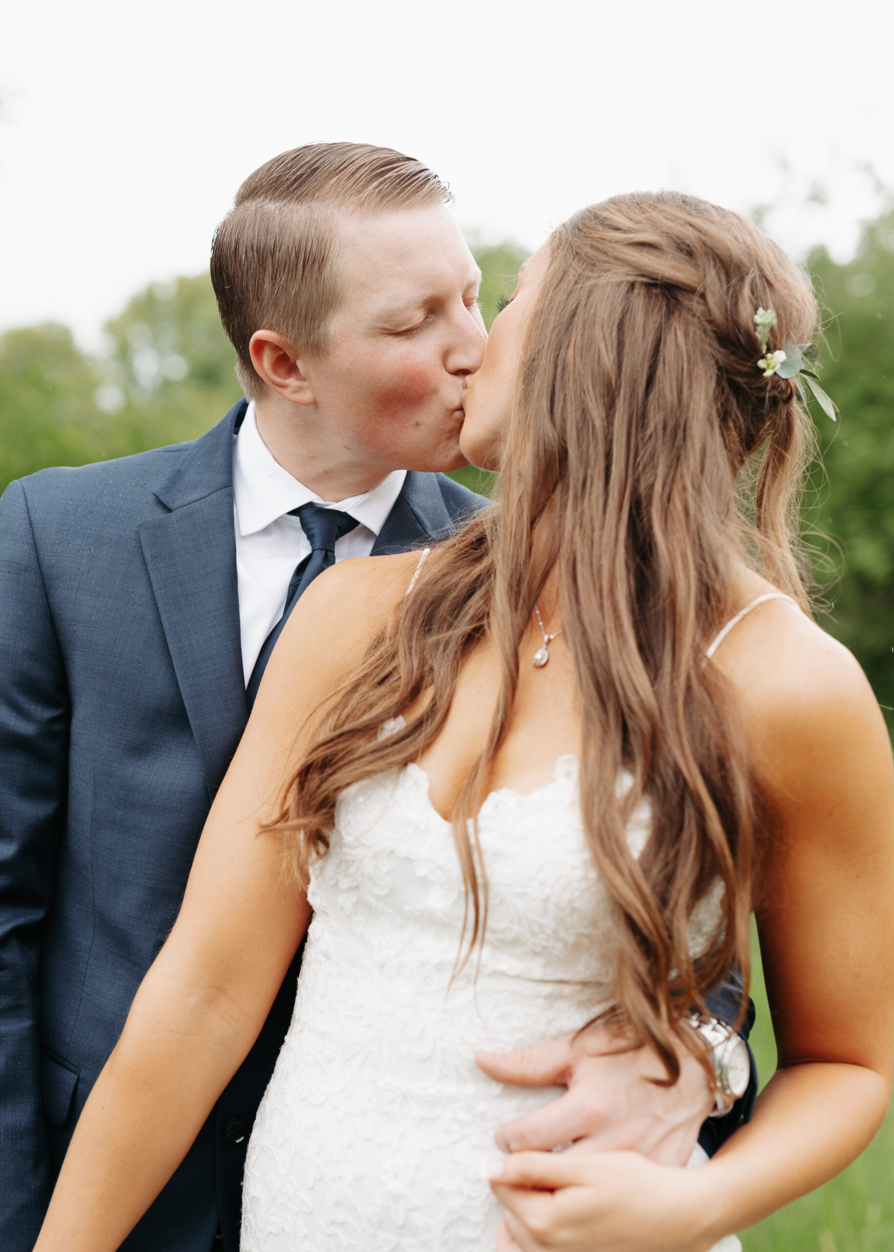 couple kissing in the rain on their wedding day holding each other close